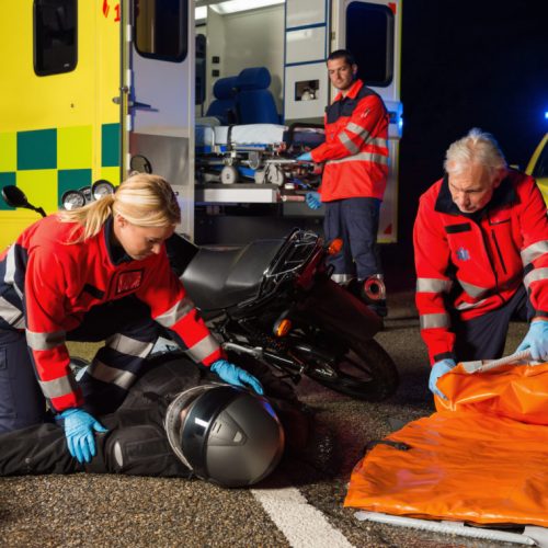 Emergency team assisting injured motorbike man driver at night